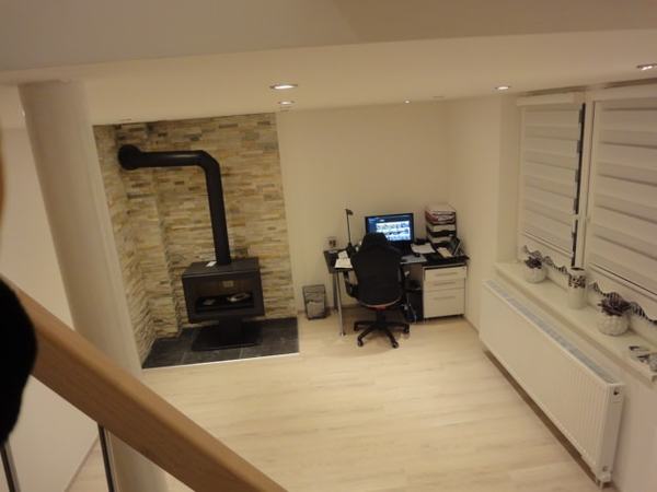 Modernes Homeoffice mit Schreibtisch, Computer, Kaminofen und heller Einrichtung.